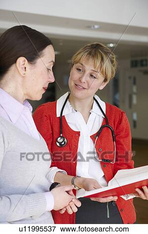 Stock Photo - Female doctor with book talking to woman. Fotosearch