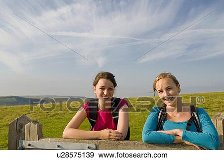 Female hikers rest on gate View Large Photo Image Stock Photo - Female hikers rest on gate. Fotosearch