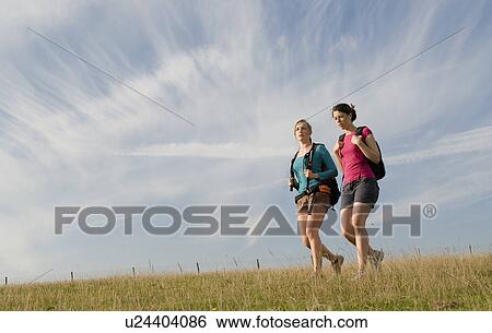 Female hikers walk on hill top View Large Photo Image Stock Photograph - Female hikers walk on hill top. Fotosearch