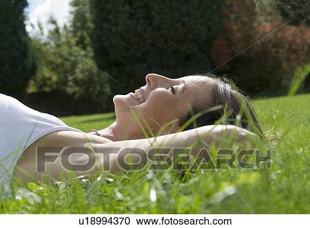 Female lying on grass smiling View Large Photo Image Stock Image - Female lying on grass smiling. Fotosearch