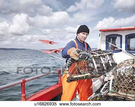 Fisherman carrying lobster pot on boat View Large Photo Image Stock Photography - Fisherman carrying lobster pot on boat. Fotosearch