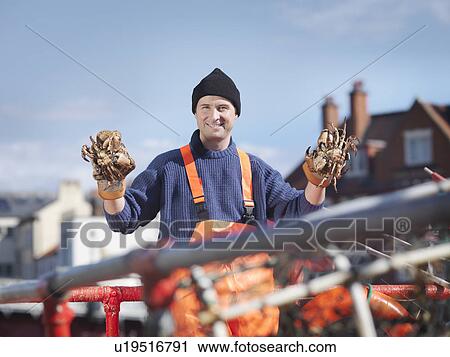 Stock Image - Fisherman holding crabs on boat. Fotosearch