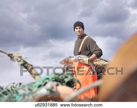 Stock Photography - Fisherman holding fish. Fotosearch