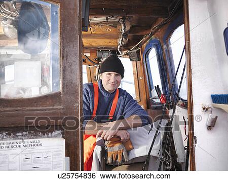 Fisherman in wheelhouse of fishing boat View Large Photo Image Stock Photograph - Fisherman in wheelhouse of fishing boat. Fotosearch
