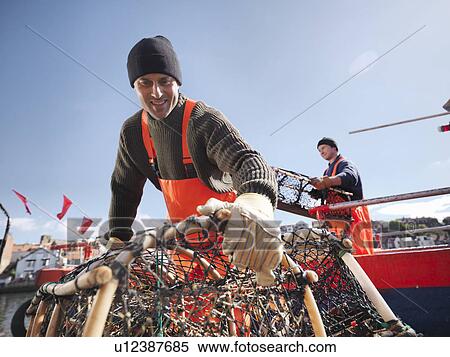 Stock Photography - Fishermen carrying lobster pots on boat. Fotosearch
