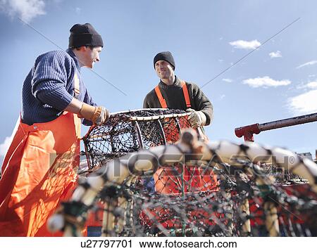 Stock Image - Fishermen loading boat with lobster pots. Fotosearch