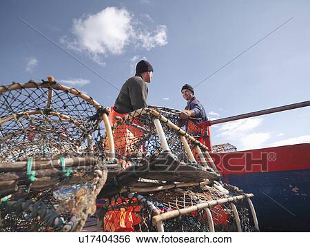 Stock Photograph - Fishermen loading boat with lobster pots. Fotosearch