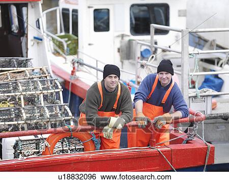 Stock Photograph - Fishermen on boat in harbour. Fotosearch