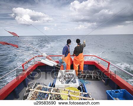 Stock Image - Fishermen on boat pointing out to sea. Fotosearch