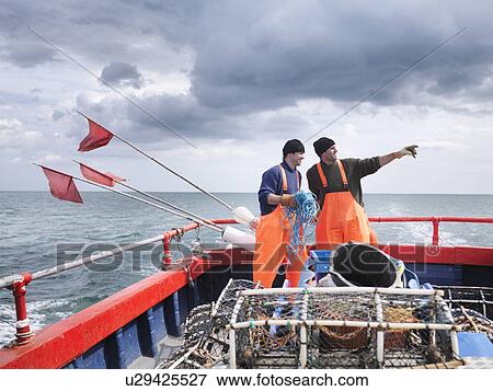 Stock Photo - Fishermen on boat pointing out to sea. Fotosearch