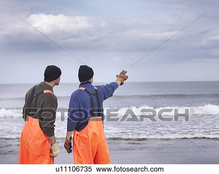 Stock Photography - Fishermen on shore pointing out to sea. Fotosearch