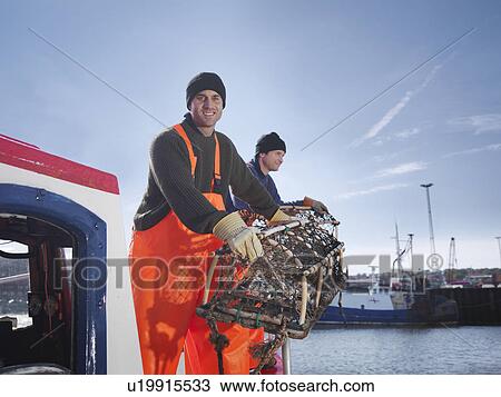 Stock Image - Fishermen with lobster pots on boat. Fotosearch