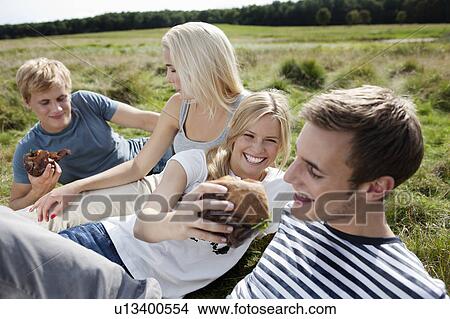 Four young persons sitting in grass View Large Photo Image Picture - Four young persons sitting in grass. Fotosearch