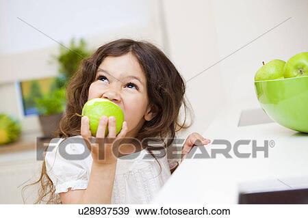 Girl biting a green apple View Large Photo Image Stock Photo - Girl biting a green apple. Fotosearch
