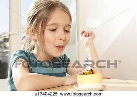 Stock Photography - Girl blowing out candle on birthday cake. Fotosearch