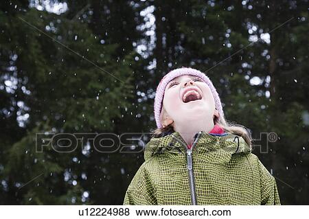 Stock Photo - Girl catching snow flakes in her mouth. Fotosearch