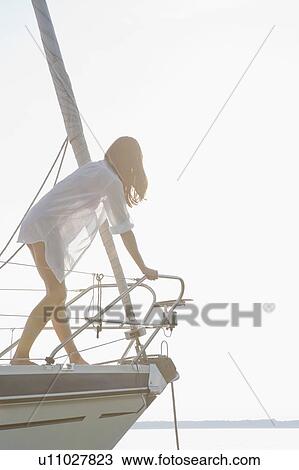 Stock Image - Girl climbing on front of boat. Fotosearch