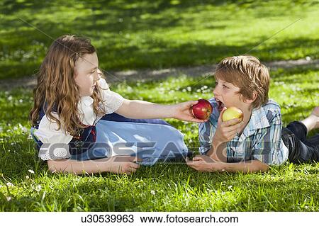 Girl feeding boy with apple View Large Photo Image Stock Image - Girl feeding boy with apple. Fotosearch
