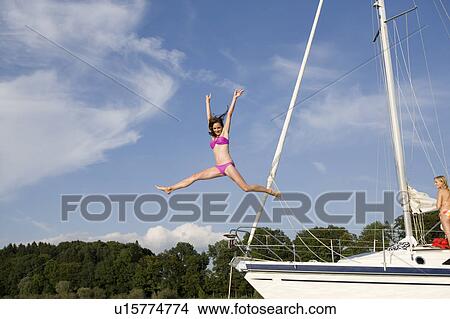 Picture - Girl jumping from boat into water. Fotosearch