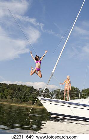 Stock Photo - Girl jumping from boat into water. Fotosearch