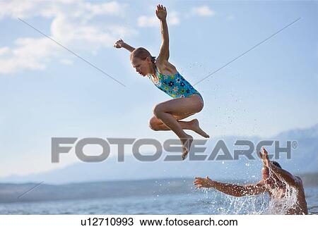 Stock Image - Girl jumping from dad¥s shoulders. Fotosearch