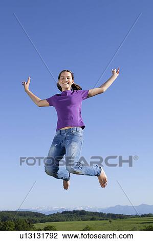 Stock Image - Girl jumping in air, happy. Fotosearch