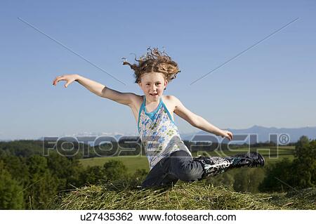 Stock Image - Girl jumping in grass. Fotosearch