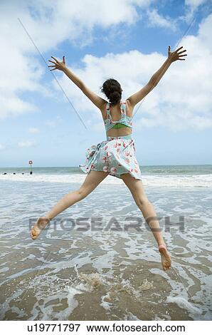 Girl leaps on waters edge View Large Photo Image Stock Photo - Girl leaps on waters edge. Fotosearch
