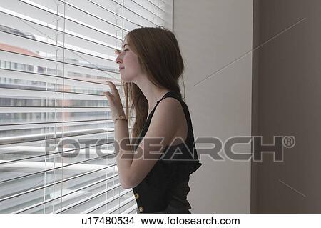 Girl looking through slatted blinds View Large Photo Image Picture - Girl looking through slatted blinds. Fotosearch