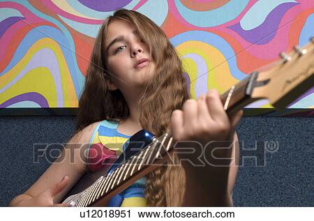 Stock Image - Girl playing guitar with funky painting. Fotosearch