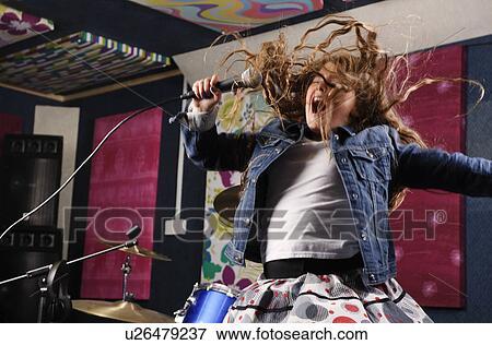 Stock Photo - Girl singing and jumping in studio. Fotosearch
