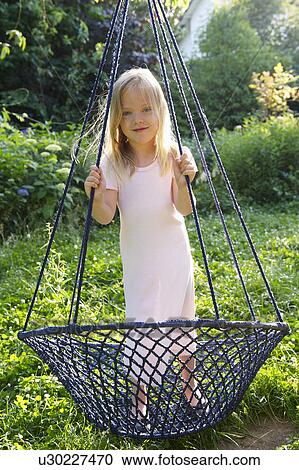 Stock Image - Girl standing on a swing. Fotosearch