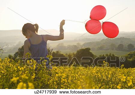 Girl walks thru field with balloons View Large Photo Image Stock Photo - Girl walks thru field with balloons. Fotosearch