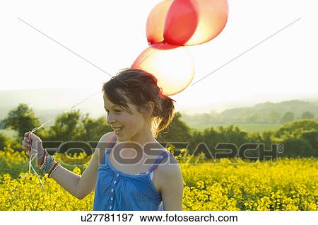 Stock Photo - Girl walks thru field with balloons. Fotosearch