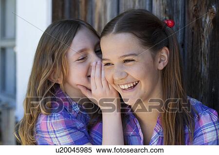 Girl whispering in her friends ear View Large Photo Image Stock Photography - Girl whispering in her friends ear. Fotosearch