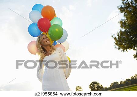 Girl with balloons outside at sunset View Large Photo Image Picture - Girl with balloons outside at sunset. Fotosearch