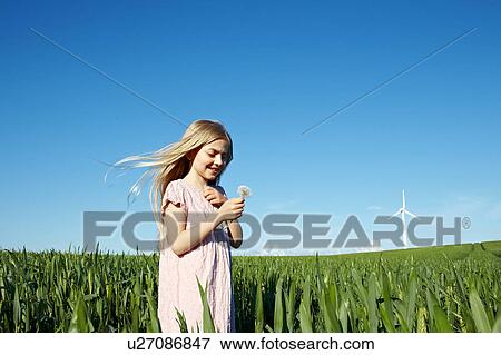 Girl with flower standing in field View Large Photo Image Stock Photo - Girl with flower standing in field. Fotosearch