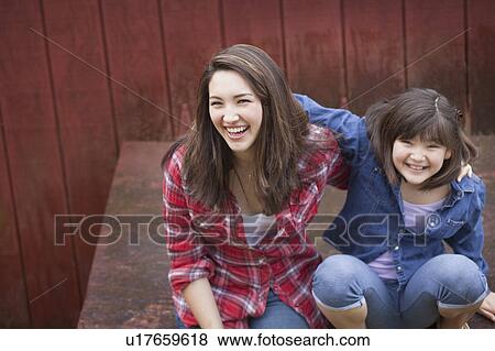Girl with sister sitting by barn View Large Photo Image Stock Photo - Girl with sister sitting by barn. Fotosearch
