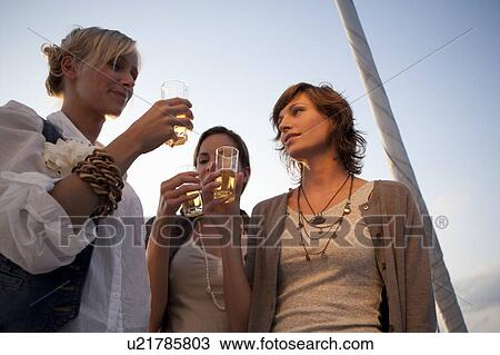 Stock Image - Girls drinking beer on boat. Fotosearch