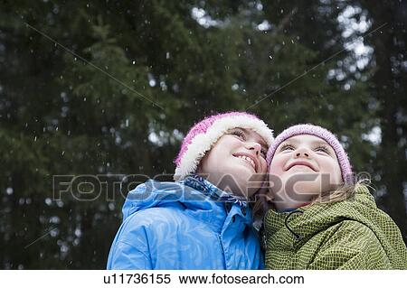 Stock Photography - Girls looking up at snowflakes. Fotosearch