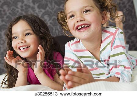 Girls lying in bed laughing View Large Photo Image Stock Image - Girls lying in bed laughing. Fotosearch