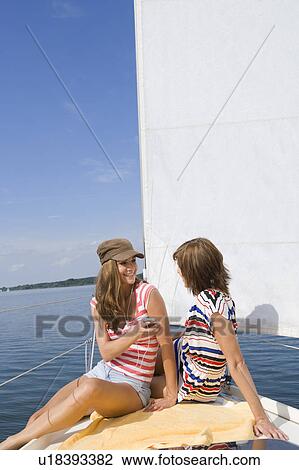 Stock Image - Girls sitting on boat. Fotosearch