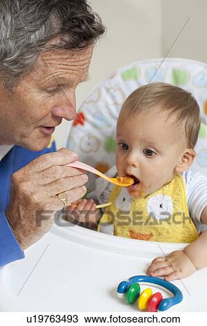 Grandad feeding grandson with baby spoon View Large Photo Image Stock Image - Grandad feeding grandson with baby spoon. Fotosearch