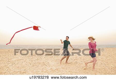 Happy couple fly kite on beach View Large Photo Image Stock Photo - Happy couple fly kite on beach. Fotosearch