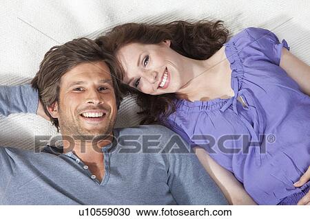 Happy couple lying on rug View Large Photo Image Stock Image - Happy couple lying on rug. Fotosearch