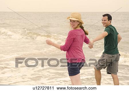 Stock Image - Happy couple paddle thru sea. Fotosearch