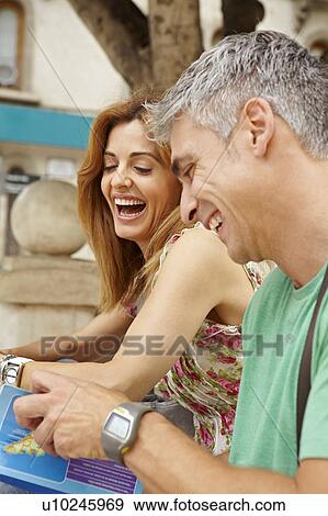 Happy couple reading guidebook View Large Photo Image Stock Photo - Happy couple reading guidebook. Fotosearch
