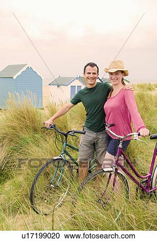Stock Image - Happy couple with bicycles on beach. Fotosearch