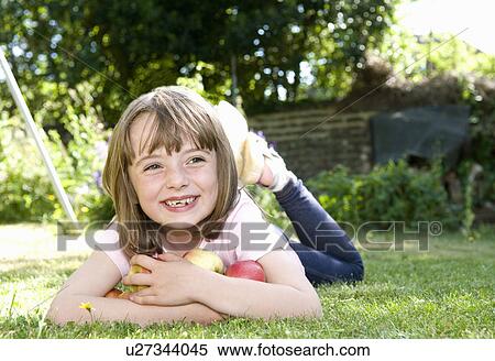 Stock Photography - Happy girl in garden with apples. Fotosearch