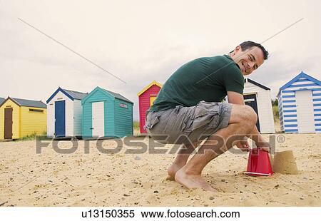 Happy man makes sandcastles on beach View Large Photo Image Stock Photography - Happy man makes sandcastles on beach. Fotosearch